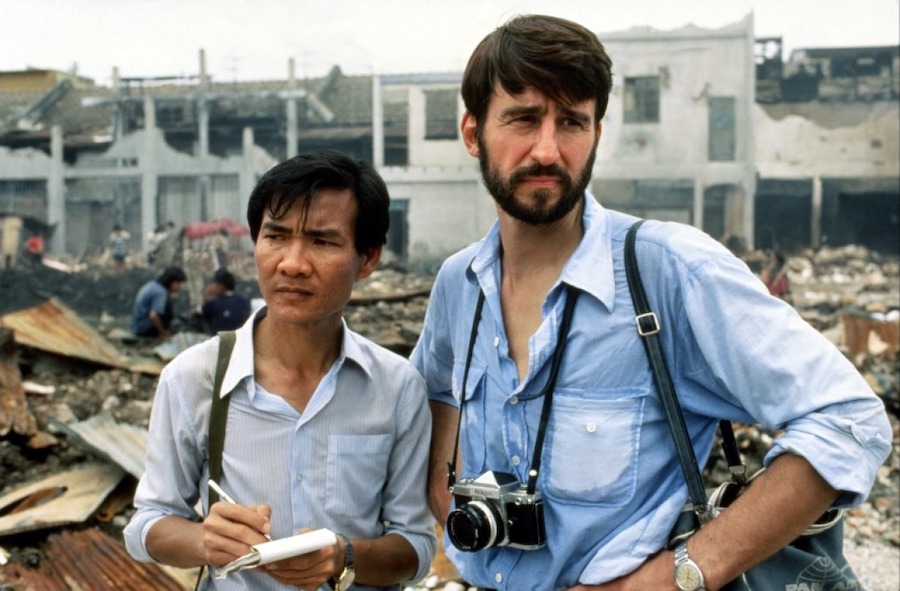 Scène du film The Killing Fields montrant deux journalistes au Cambodge dans un paysage urbain détruit par la guerre