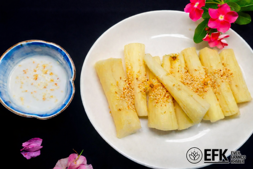 Assiette de manioc bouilli cambodgien servi avec graines de sésame et lait de coco, logo EFK en bas à droite, fond noir élégant.