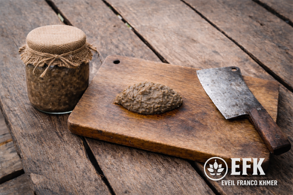 Prahok cambodgien sur planche en bois avec pot de conservation et hachoir dans une maison traditionnelle sur pilotis