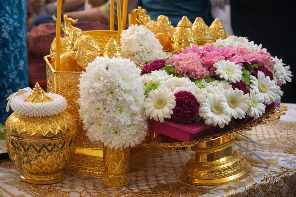 Offrandes traditionnelles khmères composées de fleurs blanches, roses et pourpres, disposées sur des plateaux dorés lors d’une cérémonie culturelle ou religieuse au Cambodge